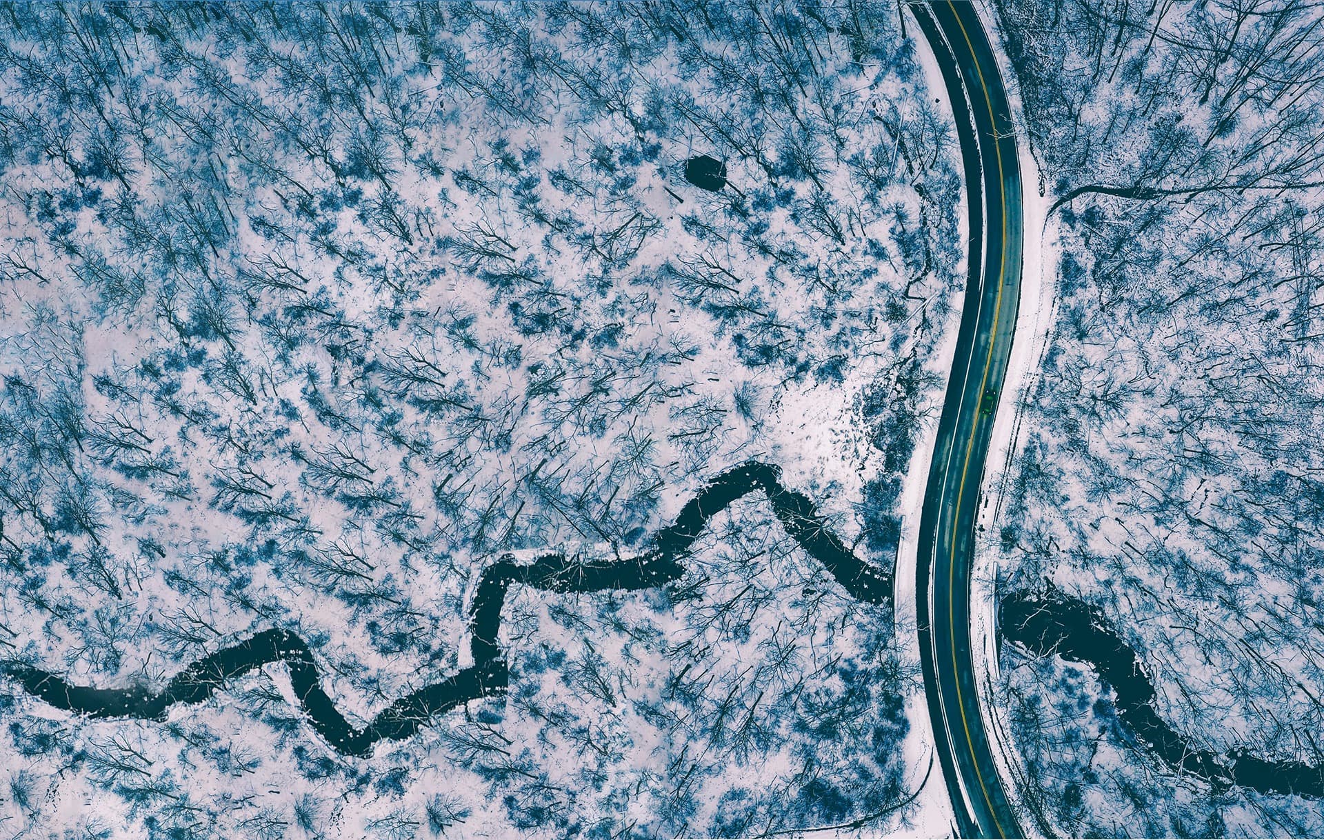 Aerial view of a treated Ontario road cutting through a snow-covered forest